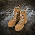 A pair of Samelin NATO Combat Boots 583 in brown suede and nylon standing in a muddy puddle. The high-top tactical boots feature a speed-lacing system and are reflected in the water on dark, wet ground.